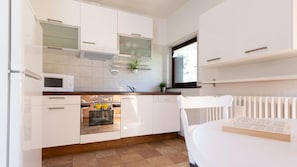 A modern kitchen with white cabinetry, a built-in microwave, and a window above the sink.