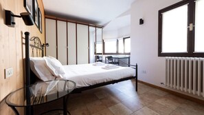A bedroom with a bed, a glass table, a radiator, and a window. - Italianway - San Gallo 16 (Valdidentro)