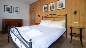 A bedroom with a bed, wooden walls, and framed pictures.