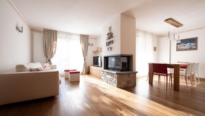 A living room with a sofa, TV, fireplace, dining table, and chairs. - Italianway - Castellazzi 14 (Bormio)