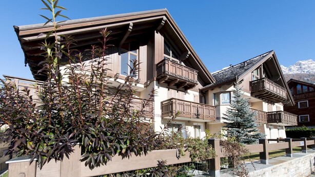 A chalet-style building with multiple balconies, wooden railings, and a snow-capped mountain backdrop. - Italianway - Castellazzi 14 (Bormio)