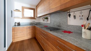 A modern kitchen with wooden cabinets, a granite countertop, and a window above the sink. - Italianway - Castellazzi 14 (Bormio)