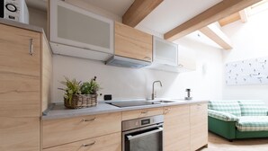 Una cocina moderna con armarios de madera, microondas integrado, pileta de acero inoxidable y horno compacto.