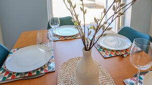 A dining table with a vase of branches, plates, and glasses. - Elements 3 bed Home in Bracklesham Bay (Chichester)