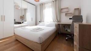 A modern hotel room with a wooden bed, a desk with a chair, a wardrobe, and a mirror. - Italianway - Bagni Nuovi 12 (Valdidentro)