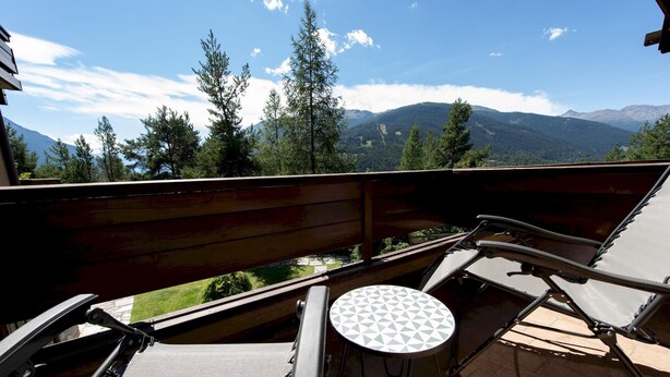 A balcony with a view of mountains, a table, and two chairs. - Italianway - Bagni Nuovi 12 (Valdidentro)