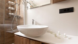 Een moderne badkamer met een groot wastafelvazen, een handdouche en een spiegel boven de wastafel.