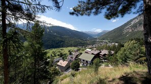 Een dorp gelegen in een bergachtig gebied, met traditionele huizen, omgeven door dichte bossen en bergen.