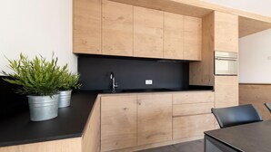 Una cocina moderna con armarios de madera, una encimera negra y una estufa empotrada.