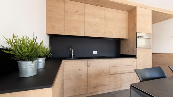 A modern kitchen with wooden cabinets, a black countertop, and a built-in stove.