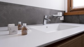 A modern bathroom with a white sink, a chrome faucet, and two bottles of liquid soap on the countertop. - Italianway - San Pietro 8 - A - Rovere - So-l563-spie8at (Valdisotto)
