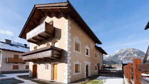 A traditional chalet with a wooden balcony, a mountain backdrop, and a clear sky. - Italianway - Funivie 6A (Bormio)