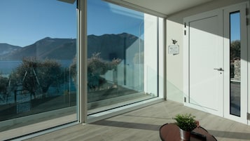 Una habitación moderna con un amplio ventanal que da a un balcón y vistas a la montaña.