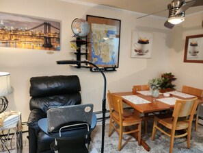 A room with a dining table, chairs, a globe, a map, a laptop, a leather chair, and a lamp.