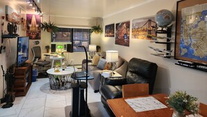 Ein modernes Wohnzimmer mit Essbereich, inklusive Deckenventilator, Wandglobus und verschiedenen Dekorationselementen.