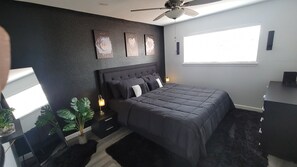 A modern bedroom with a dark-colored bed, a headboard, bedside tables with lamps, and a window providing natural light. - Centrally Located Townhome Style Condo with Fast Internet (Austin)