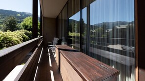 Un balcón con banca de madera y una mesa, con vistas a un paisaje montañoso.