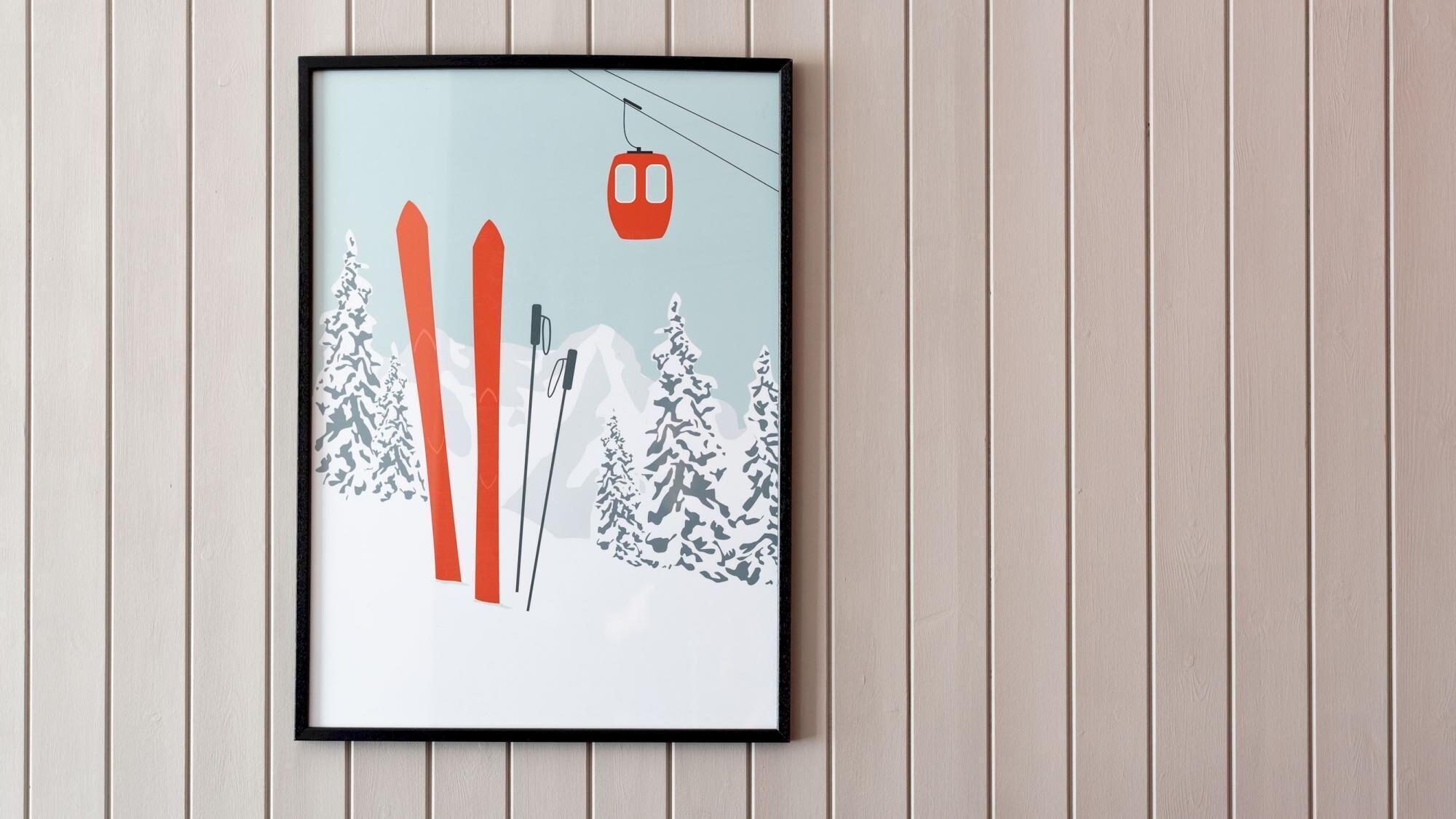 A framed picture of a ski lift with skis and snow-covered trees.