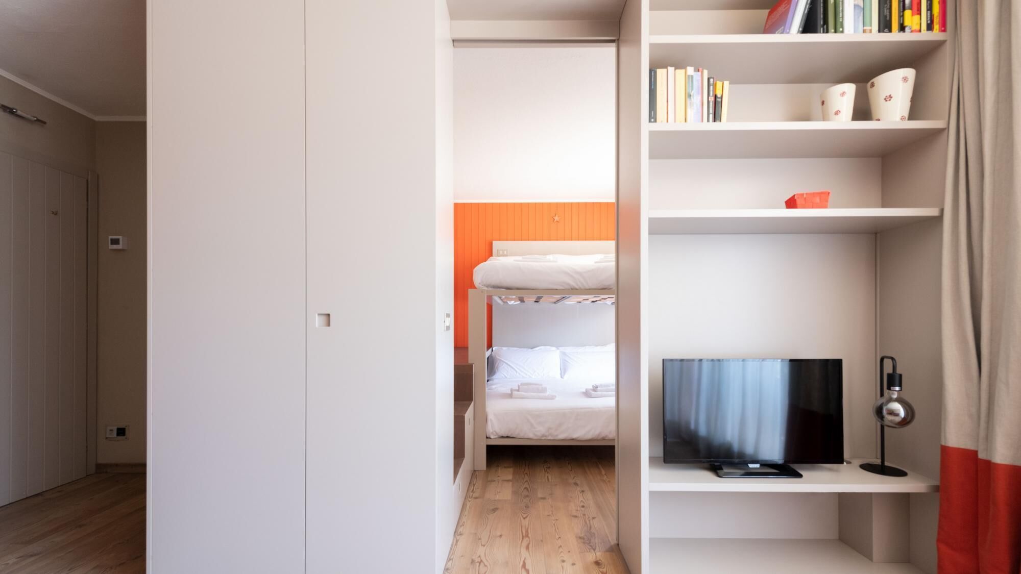 Ein Schlafzimmer mit einem Etagenbett, einem Fernseher auf einem Schrank und einem Bücherregal mit Büchern und Dekoration.