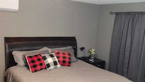 A neatly made bed with a quilted cover, a dark wooden headboard, and two bedside tables with a lamp and a vase of flowers. - Lakes-area vacation - walk to Pelican Lake, golfing, bars, restaurants and more! (Pequot Lakes)