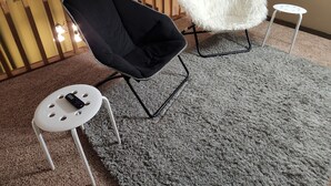 A room with a black chair, a white furry chair, and a small white table with a remote control on it. - Lakes-area vacation - walk to Pelican Lake, golfing, bars, restaurants and more! (Pequot Lakes)