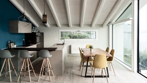 A modern kitchen with a central island, bar stools, and a dining area with a wooden table and chairs. - Villa Paloma - Maestrale Bs-e967-prov4d2 (Marone)