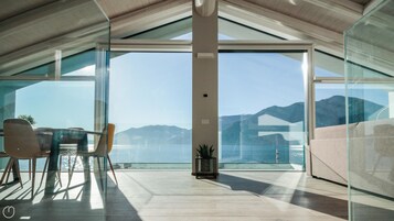 Un interior moderno con amplios ventanales de vidrio, techo de madera y vistas a montañas.