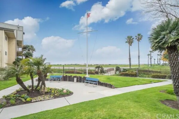A landscaped area with a flagpole, benches, and palm trees.