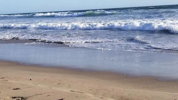 Een strand met golven die de kust naderen.