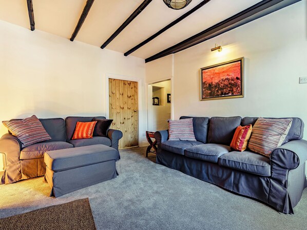 A living room with two sofas, a wooden door, and a framed picture on the wall.