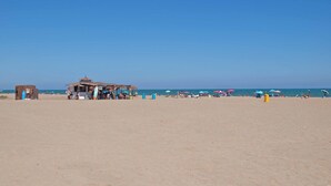 Una playa con una cabaña pequeña y sombrillas.