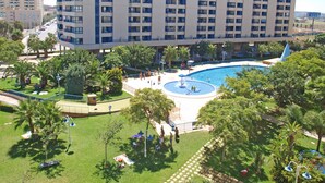 Un hotel de altura con piscina, palmeras y un césped bien cuidado.