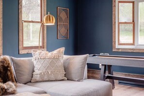 A room with a sofa, a lamp, a wall art piece, and a window.