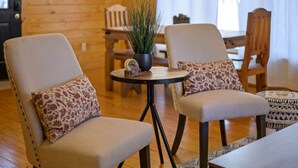 A cozy room with two upholstered chairs, a small round table with a potted plant, and a patterned rug. -  Secluded Hochatown Cabin w/ Hot Tub, Fire Pit - Sleeps 6 🌲 (broken bow)