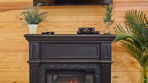 A fireplace with a TV mounted above it, surrounded by wooden paneling. -  Secluded Hochatown Cabin w/ Hot Tub, Fire Pit - Sleeps 6 🌲 (broken bow)