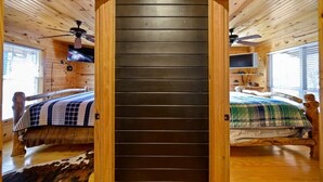 A cabin with two wooden beds, each with a ceiling fan and a TV mounted on the wall. -  Secluded Hochatown Cabin w/ Hot Tub, Fire Pit - Sleeps 6 🌲 (broken bow)