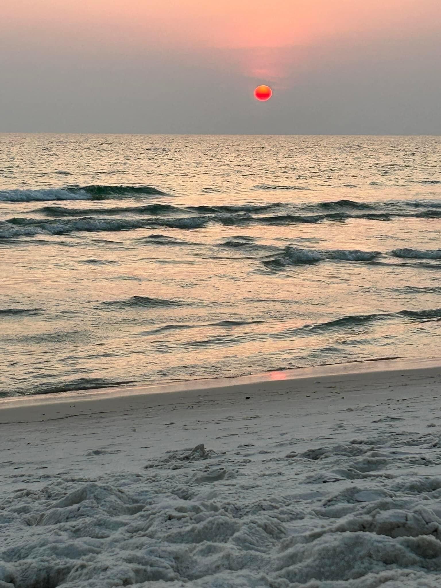 Una playa con olas y un atardecer.