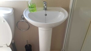 A bathroom with a toilet, sink, and shower. - Modern 6 berth caravan close to fishing lakes and beach (Burnham-on-Sea)