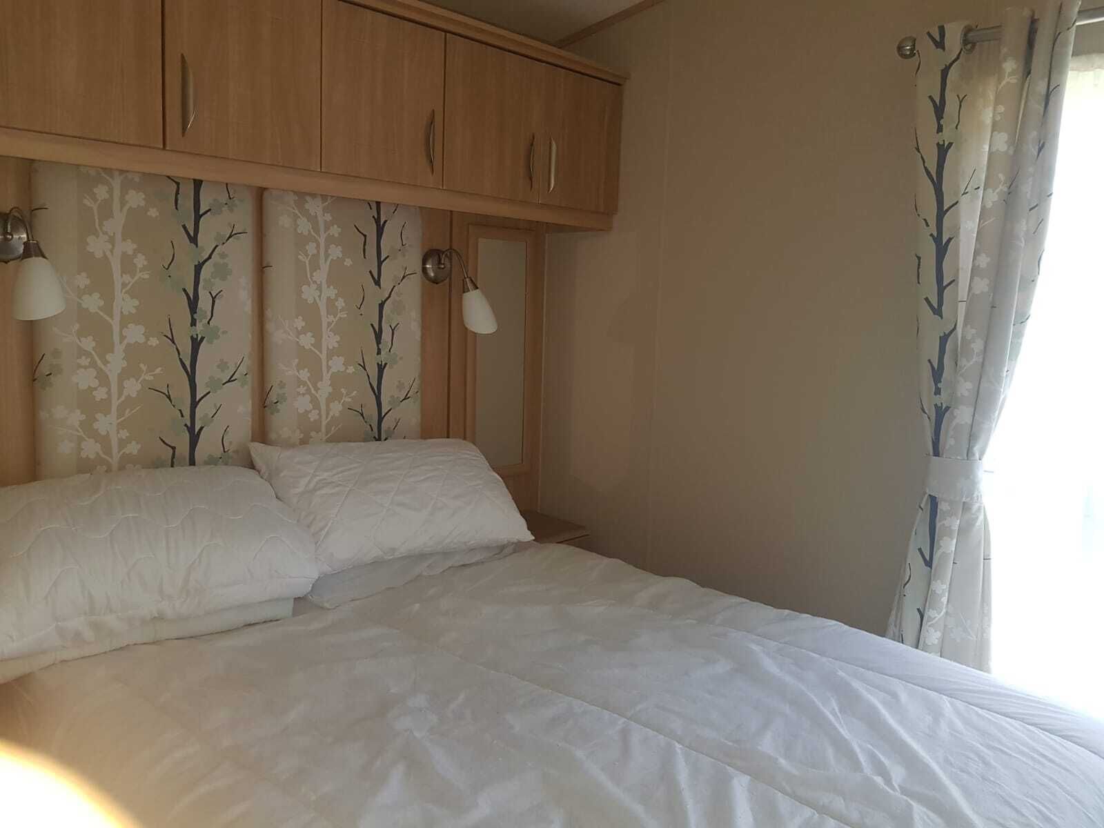 A bedroom with a bed, wooden cabinets, and two wall-mounted lamps.
