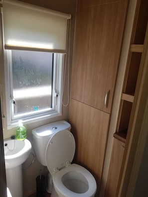 Un baño pequeño con inodoro, lavamanos y ventana.