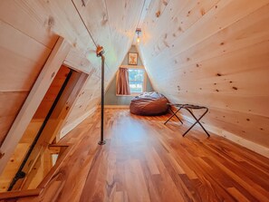 Une petite pièce mansardée aux murs en bois et au plafond en pente.