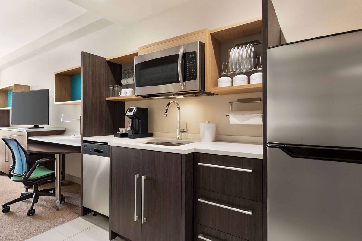 A modern kitchen with a microwave, refrigerator, and built-in coffee maker.