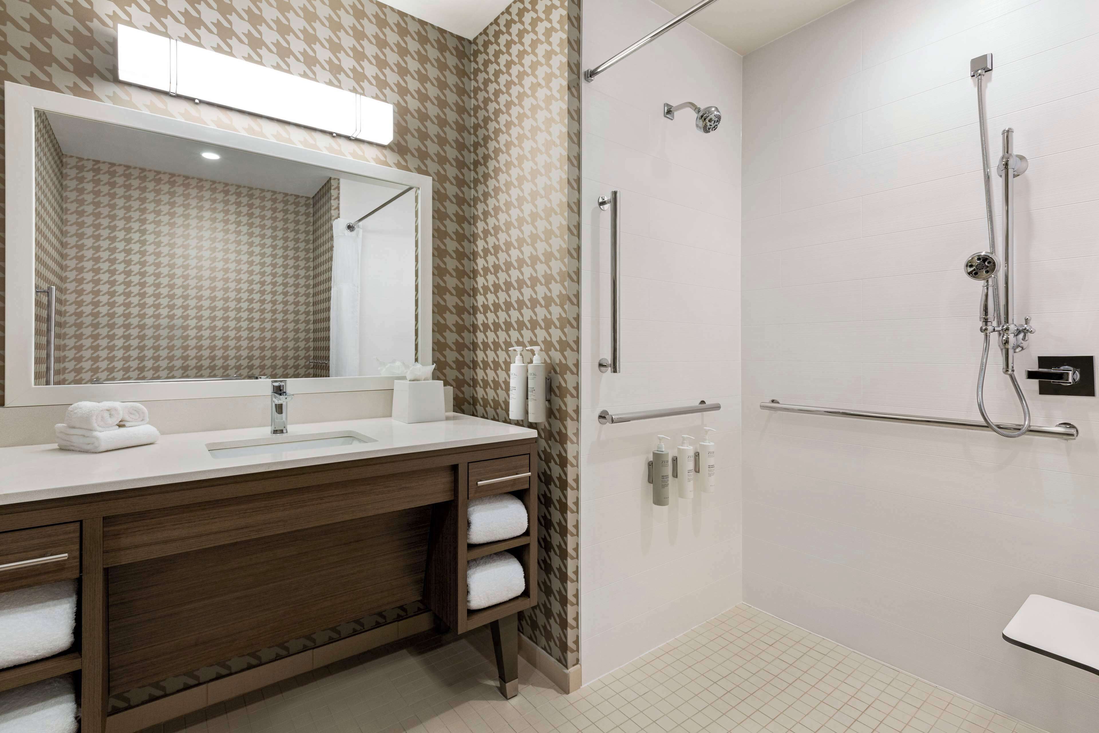 A modern bathroom with a large mirror, a sink, and a shower area.