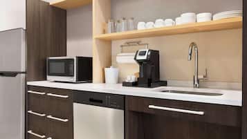 A modern kitchen with a stainless steel refrigerator, a microwave, a coffee maker, and a dishwasher.