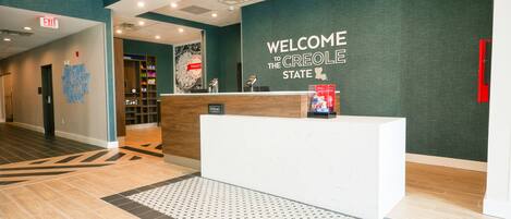 A hotel reception area with a reception desk, a welcome sign, and a wall with a map of the state.