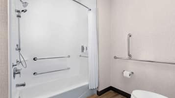 A bathroom with a white bathtub, a toilet, and a shower area.
