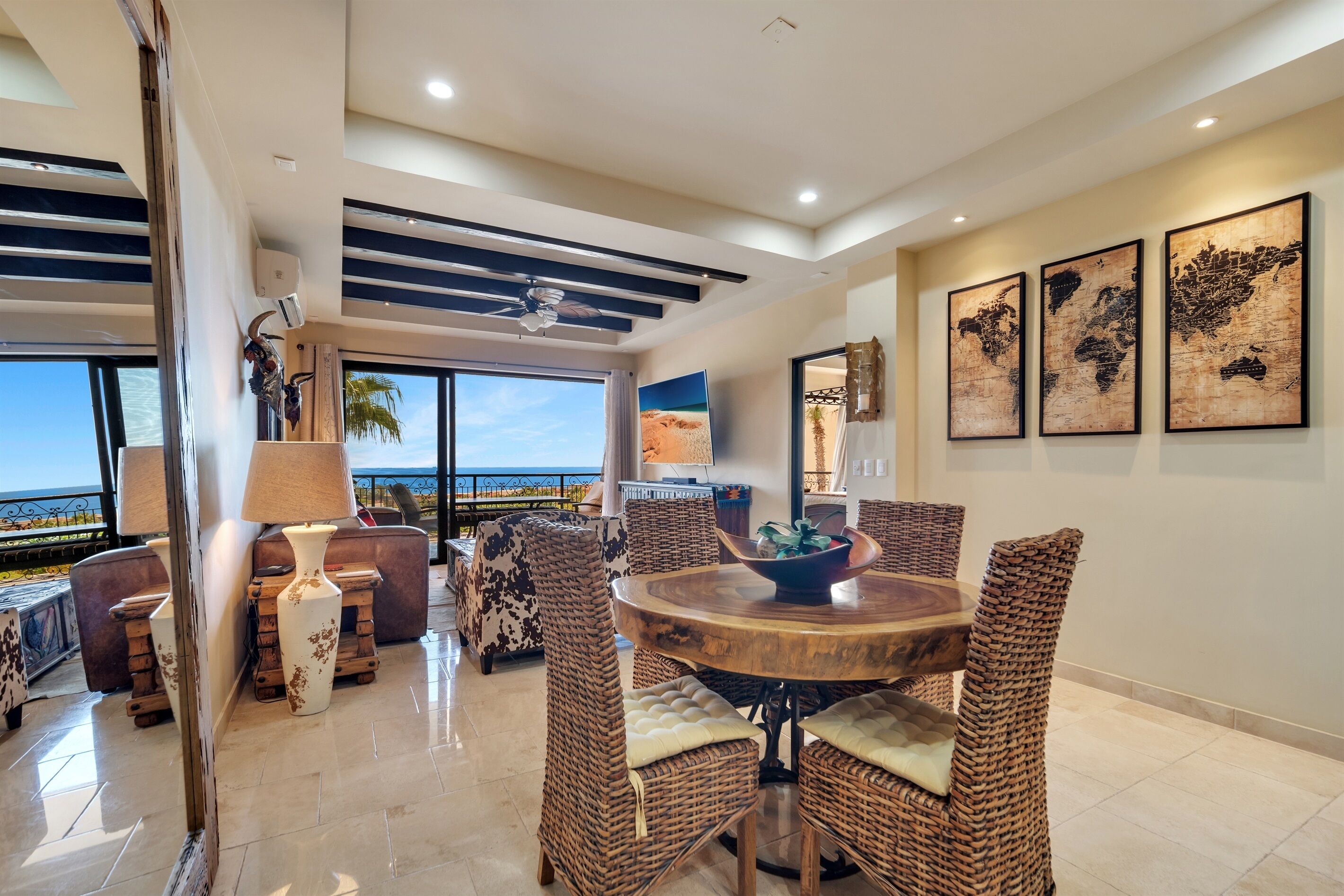 A spacious dining area with wicker furniture, a round wooden table, and a view of the ocean.