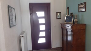 Ein Flur mit einer dunklen Tür, einem Heizkörper, einem Holzschrank und einem gerahmten Bild an der Wand.