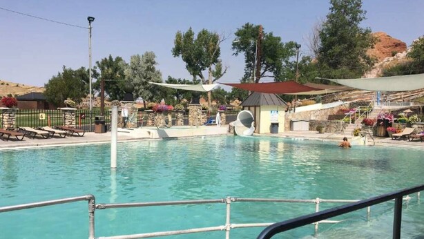 Une piscine avec un toboggan, des chaises longues et un petit pavillon.