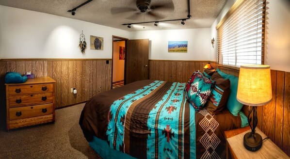 Une chambre à coucher avec un lit, une commode en bois et une lampe.